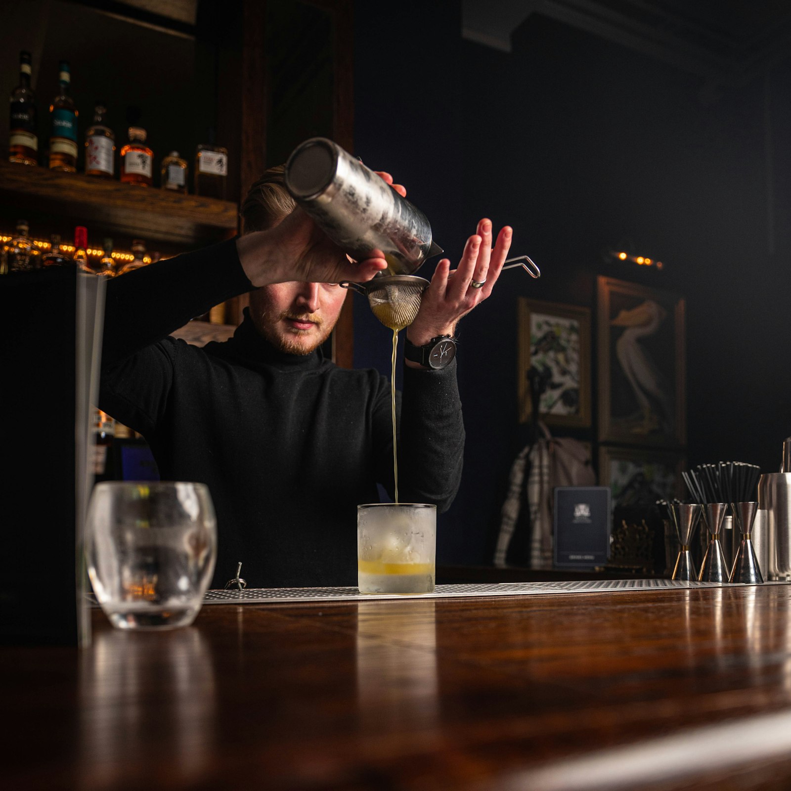 A bartender carefully pouring a drink at the bar, composure under pressure